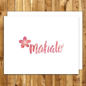 May include: White greeting cards with a watercolor design. The cards feature the word "mahalo" in a pink script font, accompanied by a pink flower. The cards are on a wooden background.