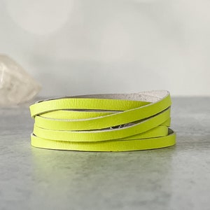 May include: A neon green leather wrap bracelet. The bracelet is made of multiple thin strips of leather, coiled in a spiral. The bright color of the bracelet makes it a bold fashion accessory.