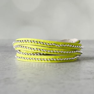May include: A neon yellow leather wrap bracelet with silver bead accents.