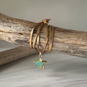 May include: A gold leather wrap bracelet with a turquoise star charm.