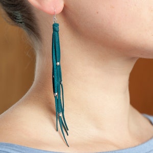 May include: Teal blue leather tassel earrings with silver beads and a silver hook.