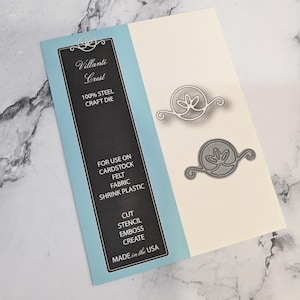 May include: A blue and white card with the text "Villanti Crest" and "100% Steel Craft Die". The card shows two metal die cuts of a decorative flourish with a leaf design.