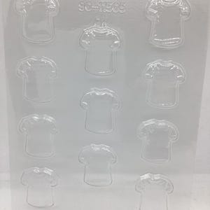 May include: Clear plastic mold with 12 t-shirt shaped cavities. The mold has the number "90-11505" printed on the top. Ideal for making chocolates, candies, or other small treats.