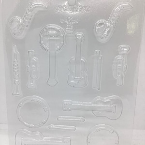 May include: Clear plastic mold with various musical instrument shapes, including saxophones, guitars, a violin, and a trumpet. The mold also features the text "90-3912".