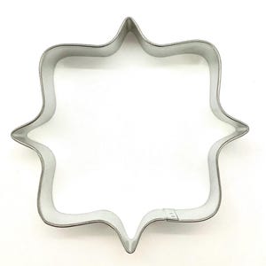 May include: A white ceramic mug with a black handle and the text "But First, Coffee" in a bold, black font. The mug is set against a blurred background, suggesting a cozy setting. The mug appears to be approximately 4 inches tall.