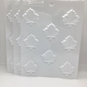 May include: Three clear plastic candy molds with a maple leaf design. Each mold has eight leaf impressions. The molds are stacked slightly, showing the CK and part number. The molds are on a white background.