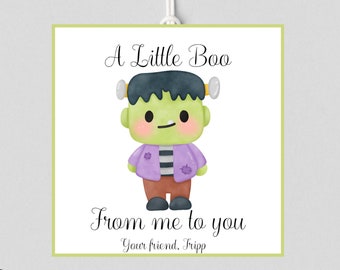 May include: Square card with a cute cartoon Frankenstein's monster illustration. The monster is green with black hair, wearing a purple jacket and brown pants. Text reads "A Little Boo From me to you" and "Your friend, Tripp".