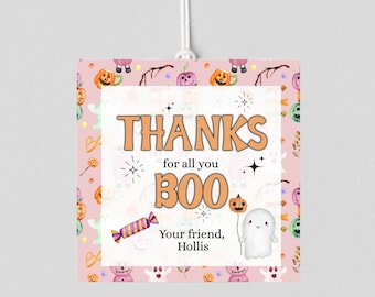 May include: A Halloween-themed gift tag with a pink background featuring pumpkins, ghosts, and candy. The tag reads "THANKS for all you BOO" with a ghost and pumpkin illustration. The tag is personalized with the name "Hollis".