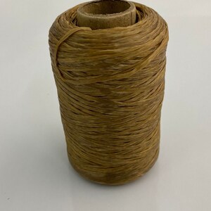 May include: A spool of brown waxed thread wound around a cardboard tube.