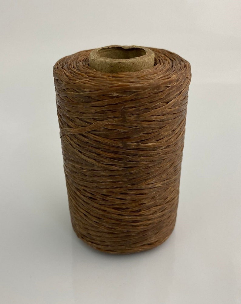 May include: A spool of brown waxed linen cord, wound around a cardboard tube.