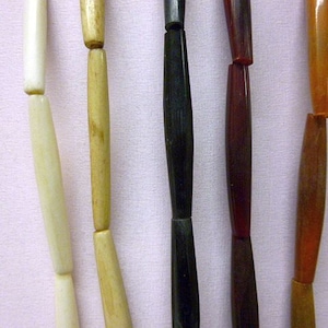 May include: Five strands of beads, each made of a different material. The beads are all the same size and shape, but they are different colors. The beads are strung on a cord and are ready to be used in a jewelry project.