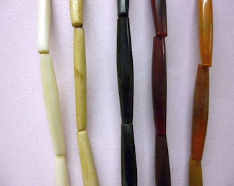 May include: Five strands of beads, each made of a different material. The beads are all the same size and shape, but they are different colors. The beads are strung on a cord and are ready to be used in a jewelry project.