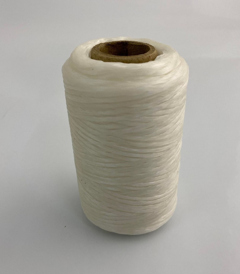 May include: A spool of white thread wound around a wooden bobbin.