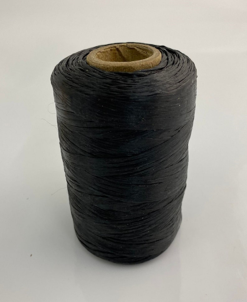 May include: A spool of black thread wound around a cardboard core.