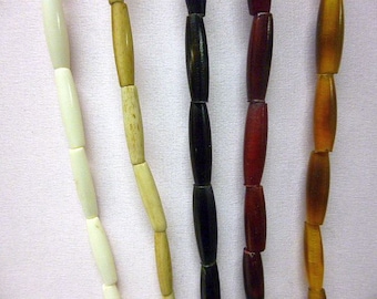 May include: Five strands of beads, each with a different color. The beads are all cylindrical and have a smooth, polished finish. The colors are white, beige, black, red, and orange.