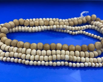 May include: A set of two strands of wooden beads, one strand is white and the other is brown. The beads are round and smooth.
