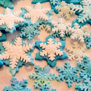 25 copos de nieve de fondant, azules y blancos con brillantina comestible. Pastel de fiesta con temática de Frozen.
