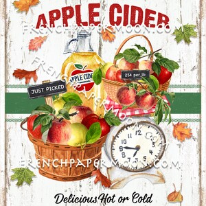 May include: A vintage-style sign advertising old-fashioned apple cider. The sign features a white wooden background with red and green accents. A basket of red and yellow apples sits on a scale with a clock face. The sign reads "Old-Fashioned Apple Cider" and "Delicious Hot or Cold Fresh Pressed & Boiled".