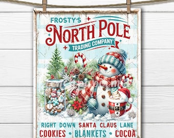 May include: A framed sign with a winter theme, featuring a snowman, candy canes, and a jar of cookies. The sign reads "Frosty's North Pole Trading Company" and includes the text "Right Down Santa Claus Lane, Cookies, Blankets, Cocoa."