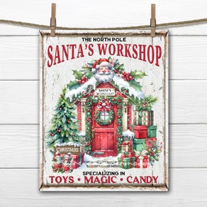 May include: A vintage-style sign with a white background and red lettering that reads "The North Pole Santa's Workshop." The sign features a cartoon illustration of Santa's workshop with a red door, a wreath, and presents. The text at the bottom reads "Specializing in Toys, Magic, Candy."