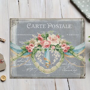 K&ouml;nnte beinhalten: Vintage-Postkarte mit grauem Hintergrund, die einen Blumenstrau&szlig; aus rosa und wei&szlig;en Rosen mit blauen und wei&szlig;en B&auml;ndern zeigt. Der Text "Carte Postale" ist oben auf der Postkarte in Schwarz gedruckt. Die Texte "Correspondance" und "Adresse" sind oben auf der Postkarte in Schwarz gedruckt.