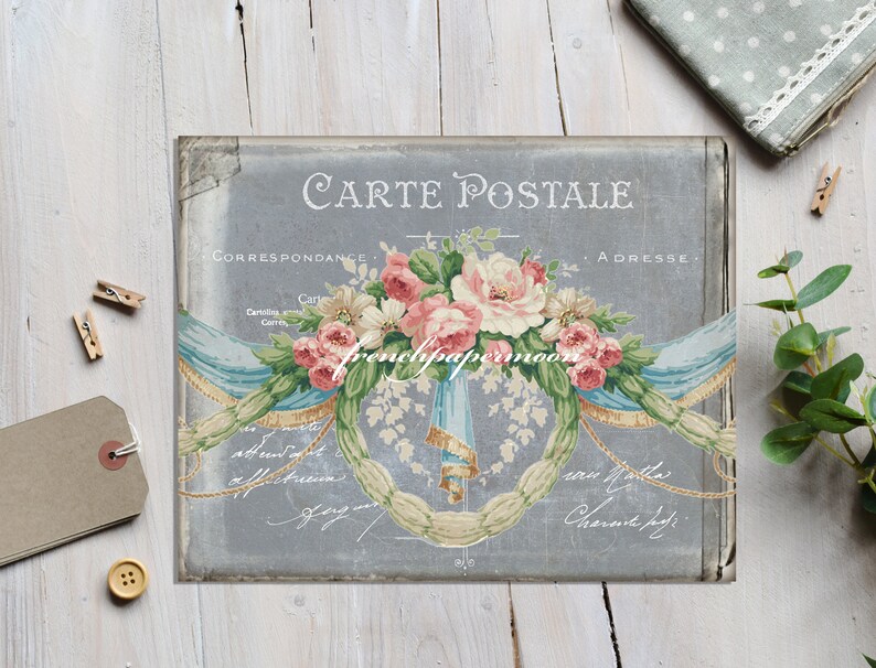K&ouml;nnte beinhalten: Vintage-Postkarte mit grauem Hintergrund, die einen Blumenstrau&szlig; aus rosa und wei&szlig;en Rosen mit blauen und wei&szlig;en B&auml;ndern zeigt. Der Text "Carte Postale" ist oben auf der Postkarte in Schwarz gedruckt. Die Texte "Correspondance" und "Adresse" sind oben auf der Postkarte in Schwarz gedruckt.