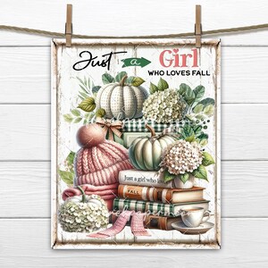 Op de afbeelding: Een wit bord met de tekst "Just a Girl Who Loves Fall" in roze en zwarte letters. Het bord is versierd met een stapel boeken, een roze gebreide muts, een witte pompoen en een boeket witte bloemen.