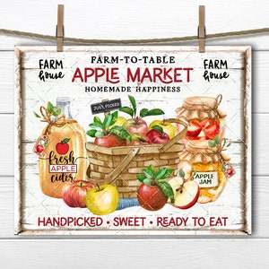 May include: A white sign with red and black text that reads "Farm house Apple Market Farm house Homemade Happiness" with a basket of red and yellow apples, a jar of apple jam, and a bottle of apple cider.