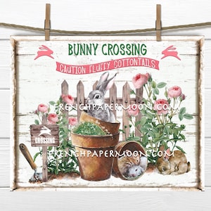 May include: A white wooden sign with the text "Bunny Crossing Caution Fluffy Cottontails" in green and pink. The sign features a white picket fence, pink roses, and two bunnies, one in a flower pot and one sleeping.