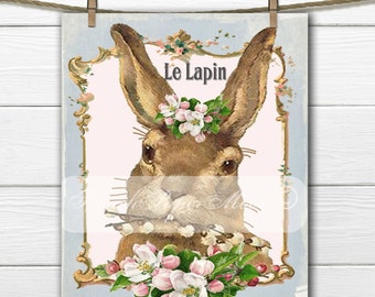 May include: A vintage illustration of a brown rabbit with pink and white flowers around its head. The rabbit is holding a branch of flowers in its mouth. The image is framed with a gold ornate frame and the text "Le Lapin" is written in black at the top of the frame.
