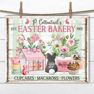 May include: A vintage-style sign for P. Cottontail's Easter Bakery, established in 1901. The sign features a pink and white storefront with a bunny rabbit, cupcakes, macarons, and flowers. The text reads "P. Cottontail's EST. EASTER BAKERY 1901 CUPCAKES MACARONS FLOWERS"