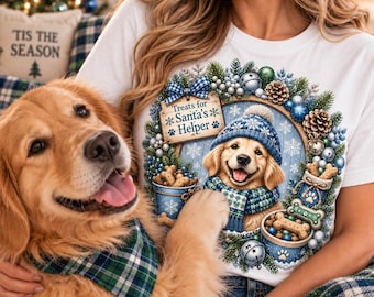 May include: A white t-shirt featuring a graphic of a golden retriever puppy wearing a blue knit hat and scarf, surrounded by a holiday wreath with blue ornaments, pine branches, and dog treats. The text reads, "Treats for Santa's Helper."