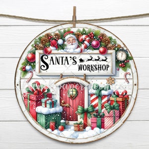 May include: A round wooden sign with a white background and a red door with a wreath. The sign says "Santa's Workshop" and is decorated with Christmas ornaments, candy canes, and presents.