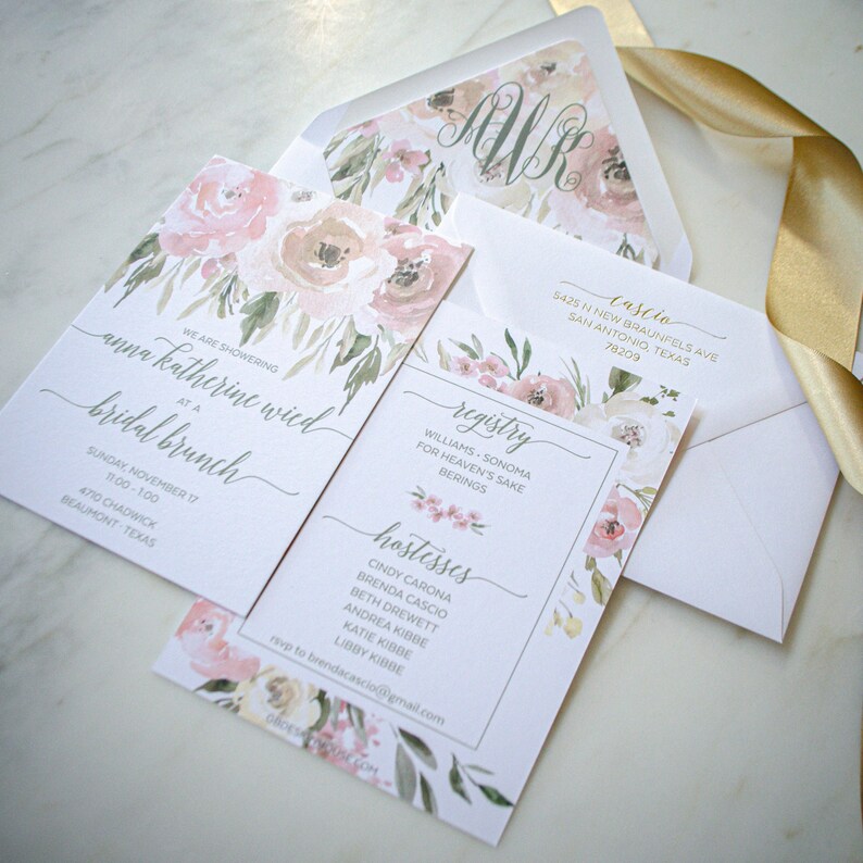 May include: A set of three cards with a floral design. The top card has the letter "M" in a script font. The middle card has the text "We are showering Anna Katherine Wied at a bridal brunch" and the bottom card has the text "Registry, Williams Sonoma for Heaven's Sake Berings, Hostesses, Cindy Carona, Brenda Cascio, Beth Drewett, Andrea Kibbe, Katie Kibbe, Libby Kibbe, RSVP to brendacascio@gmail.com".
