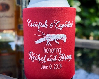 May include: A red foam beverage insulator sleeve featuring white embroidered text that reads Crawfish & Cupcakes honoring Rachel and Brian June 9, 2018, with a central white embroidered graphic of a crawfish centered on the front.