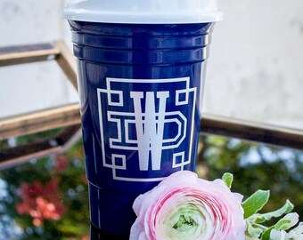 May include: A dark blue plastic tumbler with a white lid and a white geometric monogram featuring the letters DW in the center. The cup has a ribbed texture near the top rim and a smooth body, displaying a clean and functional design for beverages.