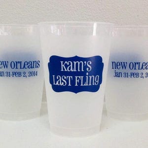 May include: Three translucent frosted plastic cups featuring blue text. The center cup displays a blue label shape with the text "Kam's LAST FLING". The side cups show the text "new orleans" and "jan 31-FEB 2, 2014" printed in blue ink.