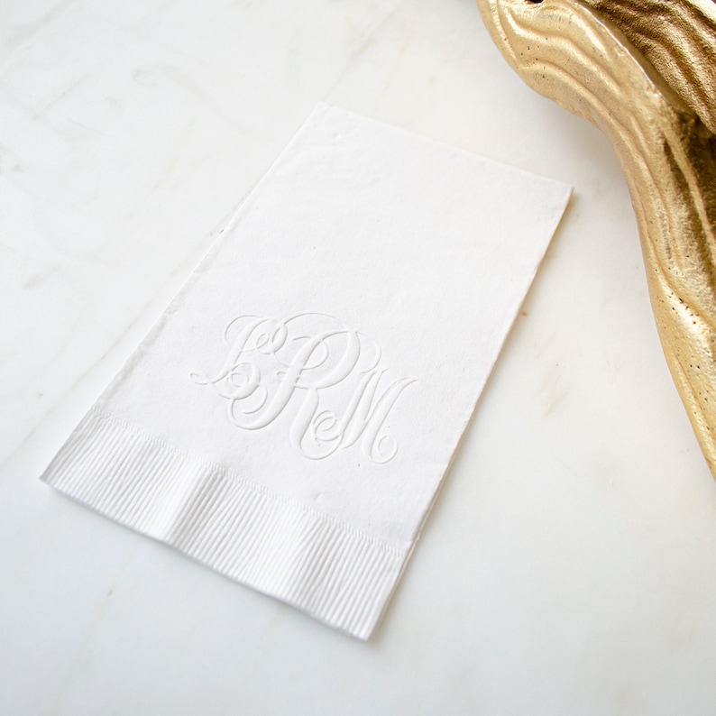 May include: White linen napkin with a monogram of the letters "SRM" embossed in the center.