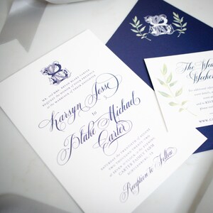 May include: A white wedding invitation with blue calligraphy announcing the marriage of Karsyn Jesse to Blake Michael Carter. The invitation details the date, time, and location of the wedding ceremony and reception. The invitation features a blue and white floral monogram.