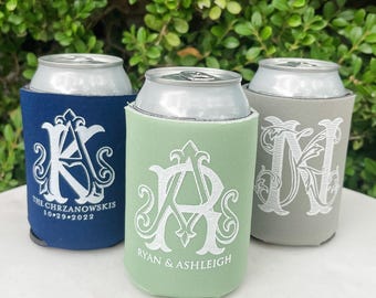 May include: Three beverage can coolers in navy blue, sage green, and gray. The navy cooler features a white monogram with "THE CHRZANOWSKIS" and "10.29.2022". The green cooler has a white monogram with "RYAN & ASHLEIGH". The gray cooler displays a white letter N.