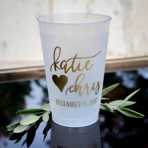 May include: White plastic cup with a gold heart and the names "katie" and "chris" written in cursive. The date "December 9, 2017" is written below the names.