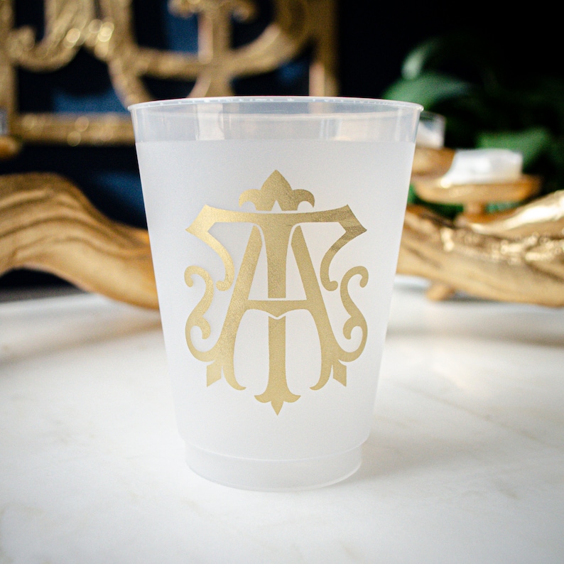 May include: A frosted plastic cup with a gold monogram of the letters "A" and "S" in a decorative font.