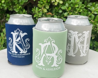 Può includere: Tre refrigeratori per lattine in blu navy, verde salvia e grigio chiaro. Ognuno presenta un monogramma ricamato in bianco con nomi e date: THE CHRZANOWSKIS 10.29.2022 sul blu, RYAN & ASHLEIGH sul verde e una grande lettera N sul grigio.