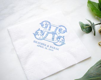May include: A square white paper napkin featuring a blue decorative monogram of the letters H and B. Below the monogram, the text reads HEATHER & BARAK and APRIL 18, 2020 in a blue serif font. The napkin has a textured border on two sides.