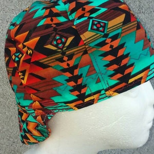 May include: A turquoise, orange, red, and black patterned surgical cap with a geometric design.