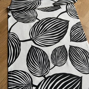 Puede incluir: Caminero de mesa blanco y negro con un patrón de hojas. Las hojas son estilizadas y tienen un diseño a rayas.