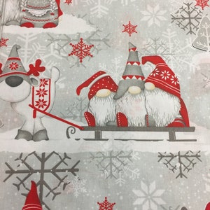 May include: A white fabric with a repeating pattern of red and white gnomes, snowflakes, and trees. The gnomes are wearing red hats and have white beards. Some of the gnomes are pulling a sled.
