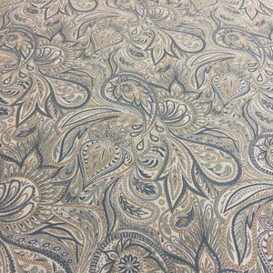 May include: A fabric with a paisley pattern in shades of blue, brown, and beige. The pattern is intricate and detailed, with a variety of shapes and sizes.