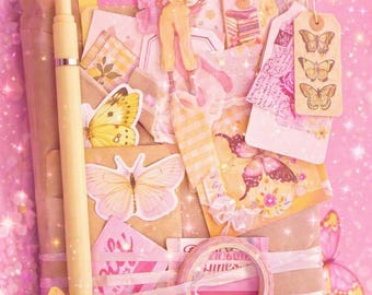 Peut inclure: Un paquet en papier kraft décoré de découpages de papillons jaunes et roses, un stylo jaune, un rouleau de ruban adhésif washi à rayures roses et divers éléments en papier incluant une petite figurine, des étiquettes et des cartes.