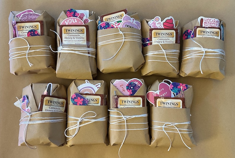 May include: Ten brown paper packages tied with white string, each containing a tea bag and decorative stickers. The tea bags are labeled "Twinings Camomile, Honey & Vanilla". The stickers have floral and inspirational designs.